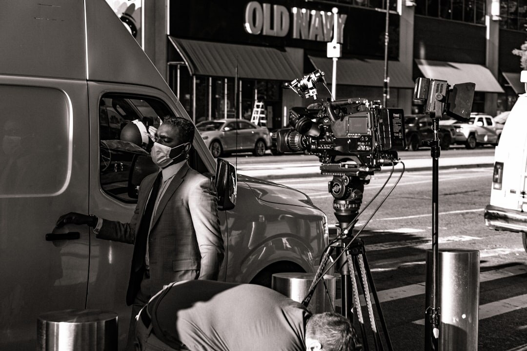 Reporter and camera operator filming a live report with a satellite van nearby